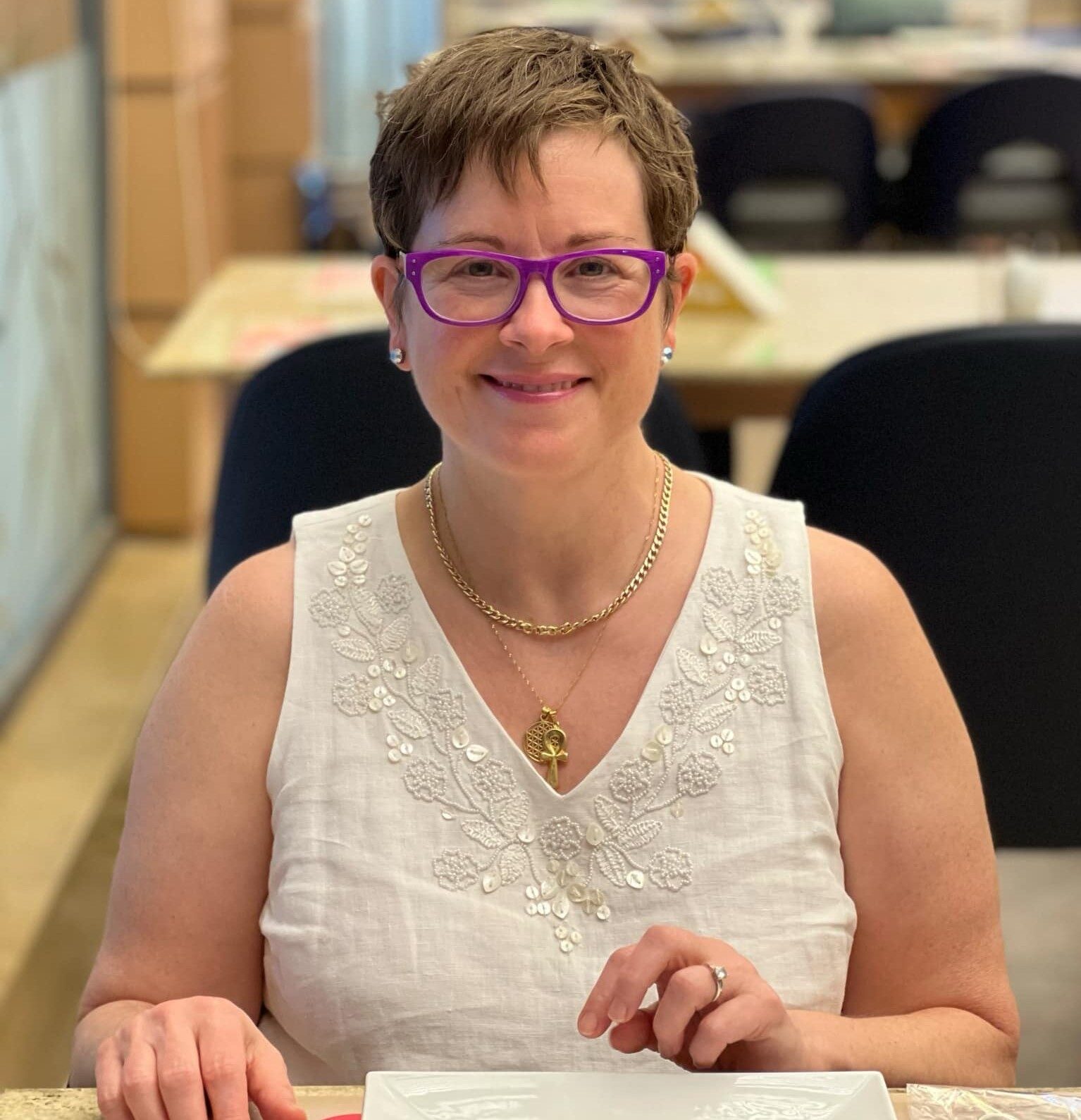 Image of Anne Moore sitting at desk facing the camera and smiling.